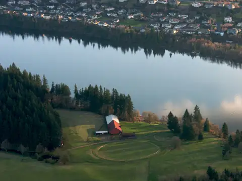 Aerial view of Lacamas Lake in Camas, Washington, with a red barn and fields on the shore